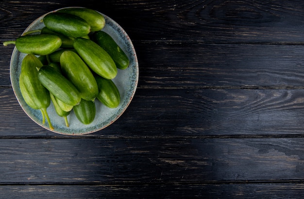 Top view of cucumbers in plate on wood with copy space