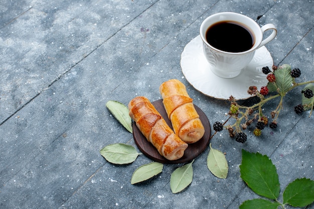 Top view of cup of coffee along with yummy bangles on grey wooden, sweet bake pastry cake sugar