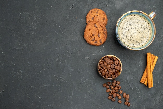 Top view a cup of coffee bowl with coffee seeds cinnamon sticks bircuits on dark isolated background