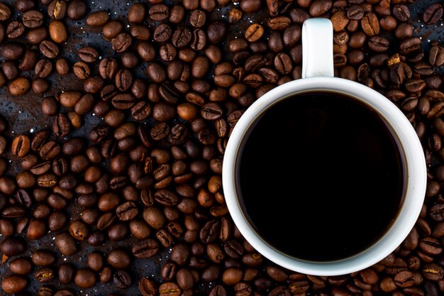 Top view of a cup of coffee on brown roasted coffee beans background