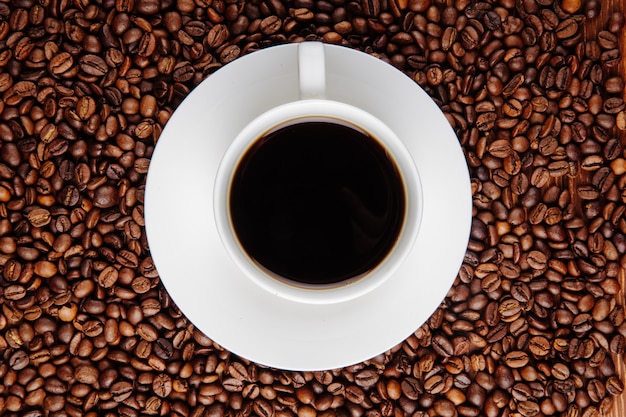 Top view of a cup of coffee on coffee beans background