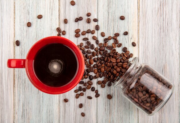 木製の背景にガラスの瓶からこぼれるコーヒーとコーヒー豆の上面図