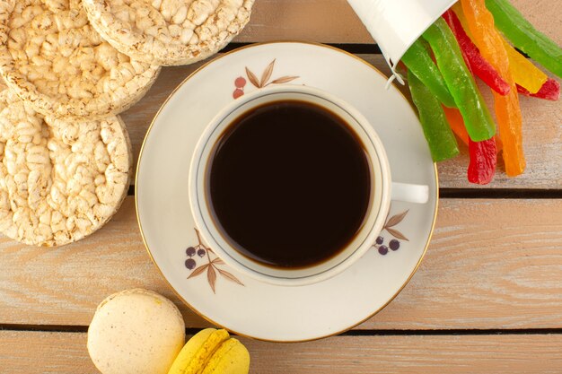 A top view cup of coffee hot and strong with french macarons and marmalade on the cream colored rustic desk drink coffee photo strong sweeties