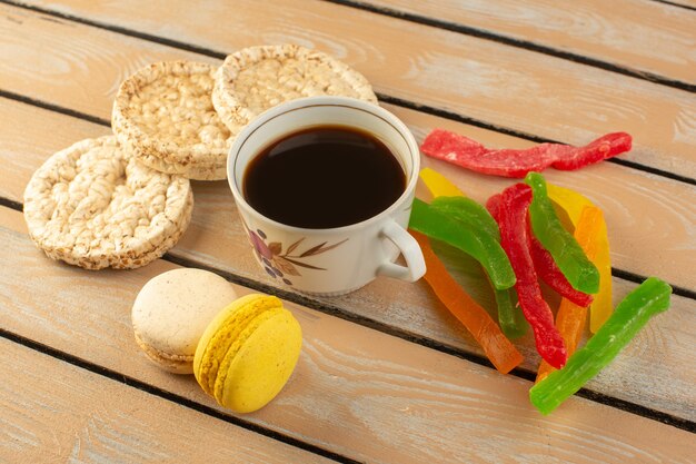 A top view cup of coffee hot and strong with french macarons and marmalade on the cream colored rustic desk drink coffee photo sugar