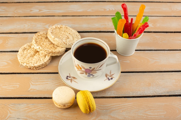 Чашка горячего и крепкого кофе, вид сверху с французскими макаронами и мармеладом на кремовом деревенском столе напиток кофе фото крепкий