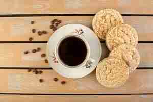 Free photo a top view cup of coffee hot and strong with fresh brown coffee seeds and crackers on the cream rustic desk coffee seed drink photo grain