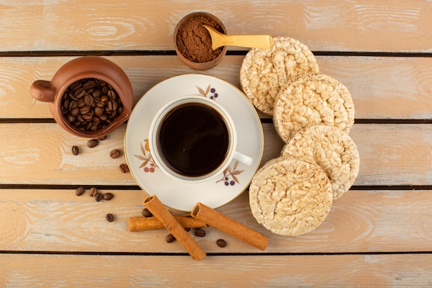 A top view cup of coffee hot and strong with fresh brown coffee seeds and crackers on the cream rustic desk coffee seed drink photo grain
