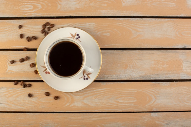 Una tazza di caffè con vista dall'alto calda e forte con semi di caffè marroni freschi sul grano rustico crema della foto della bevanda del seme del caffè dello scrittorio