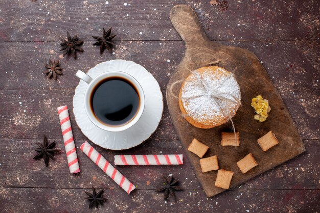 Вид сверху на чашку крепкого и горячего кофе вместе с печеньем и бисквитным тортом на деревянном коричневом столе, фруктовый торт, кофейное печенье, сладкое