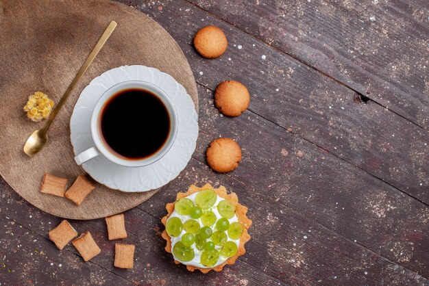 Top view of cup of coffee strong and hot along with cookies and grape cake on wooden desk, fruit bake cake coffee biscuit