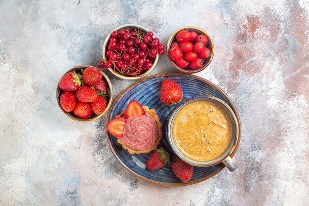 Top view cup of coffee with cake and red fruits on light table cake biscuit sweet