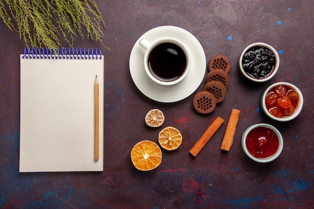 Вид сверху чашка кофе с шоколадным печеньем и фруктовым джемом на темном фоне сладкое фруктовое печенье бисквитное сладкое