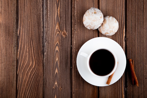 top view Cup of coffee with cinnamon and gingerbread on the right with copy space on wooden background