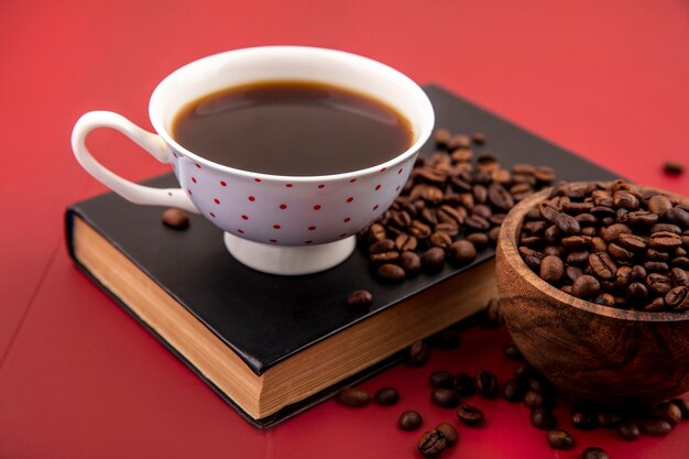 Top view of a cup of coffee with coffee beans isolated on a red background