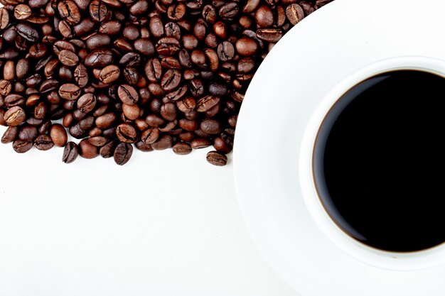 Top view of a cup of coffee with coffee beans on white background with copy space