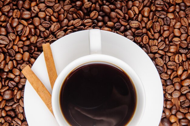 Top view of a cup of coffee with crispy sticks on coffee beans background