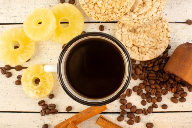 A top view cup of coffee with fresh brown coffee seeds cinnamon crackers