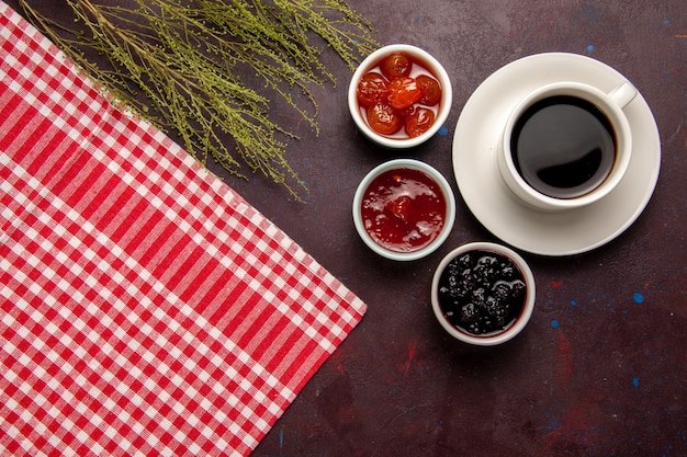 Top view cup of coffee with fruit jams on dark desk sweet fruit biscuit marmalade jam