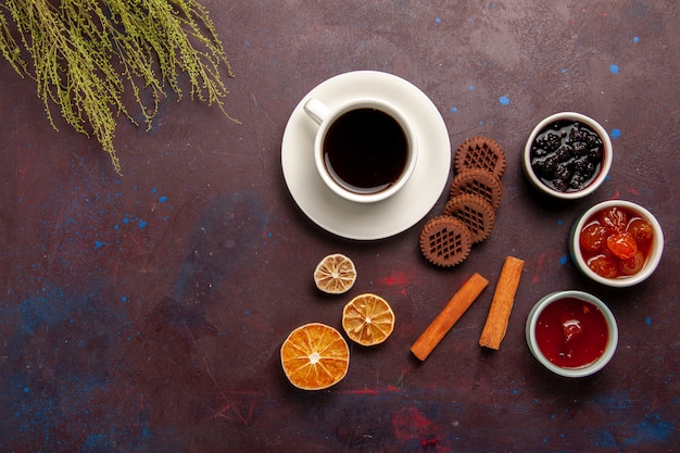 Top view cup of coffee with jams and chocolate cookies on dark background fruit jam marmalade sweet