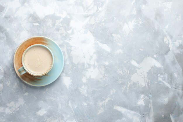 白い机の上のカップの中に牛乳とコーヒーのトップビューカップコーヒー牛乳デスクの色を飲む