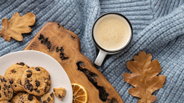 Top view of cup of coffee with sweater and autumn leaves