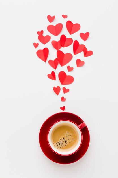 Top view of cup of coffee with valentines day paper heart shapes