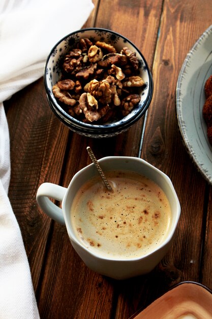 Top view of a cup of coffee with walnuts in a bowl