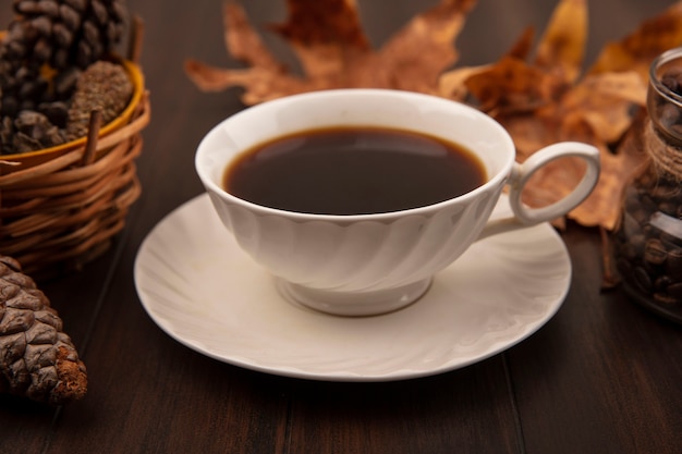 황금 노란 잎과 소나무 콘 나무 표면에 고립 된 맛을 낸 커피 한 잔의 상위 뷰