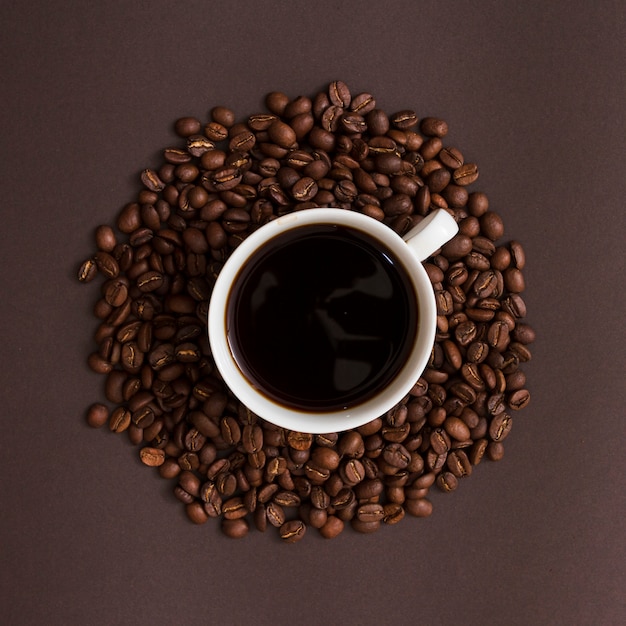 Free photo top view cup and grains of coffee