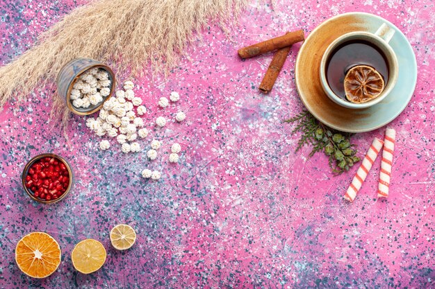 Бесплатное фото Вид сверху чашка чая с белыми сладкими конфитюрами и корицей на светло-розовой поверхности