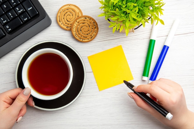 Вид сверху чашка чая с письменными мотивационными заметками на белом фоне сладкая деловая клавиатура женский перерыв в офисе
