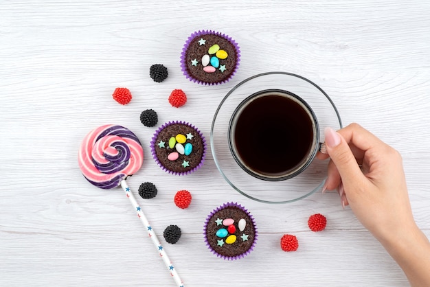 Free photo a top view cup of tea along with lollipop and candies on white, drink candy color