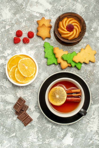 Top view cup of tea biscuit in bowl chocolate on grey surface