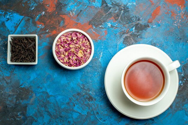 上面図乾燥した花びらと青赤の表面にお茶と茶碗のカップ