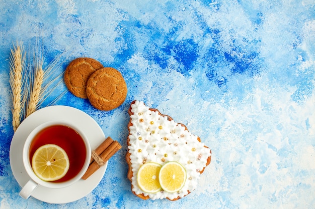 Вид сверху чашка чая, торт с лимонным печеньем на синем столе, свободное пространство