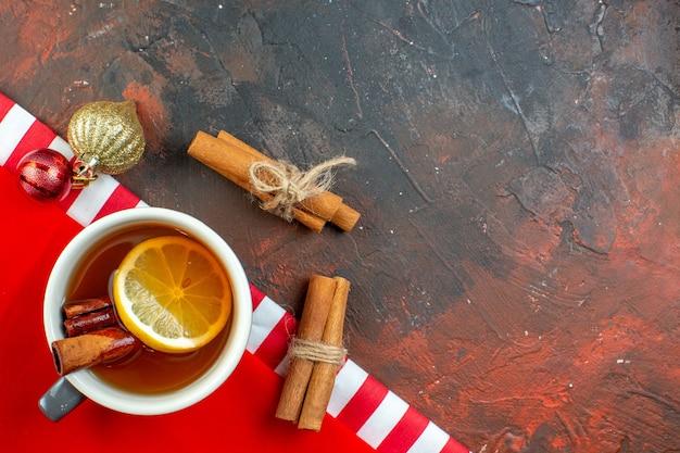 Free photo top view cup of tea cinnamon sticks on dark red background