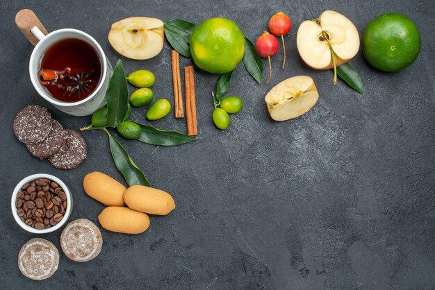 Top view a cup of tea citrus fruits a cup of herbal tea cinnamon sticks apples cookies