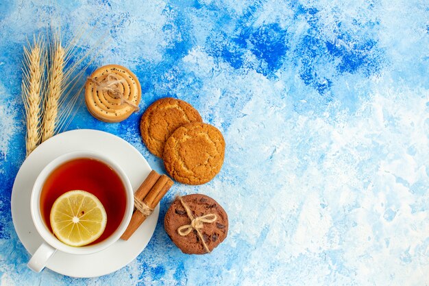 Top view cup of tea cookies on blue table with copy space