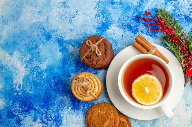 Top view cup of tea cookies tied up with rope on blue table free space