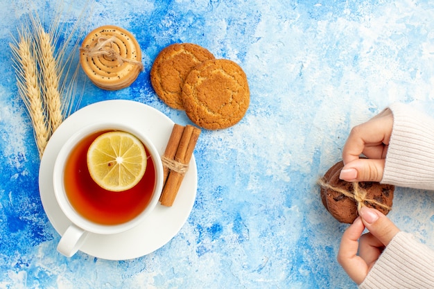 Free photo top view cup of tea cookies tied with rope in female hand on blue table free space