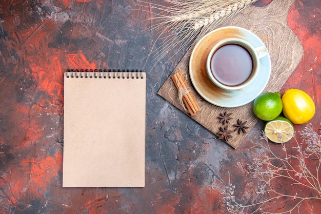 Top view a cup of tea a cup of tea star anise lemon cinnamon on the cutting board white notebook