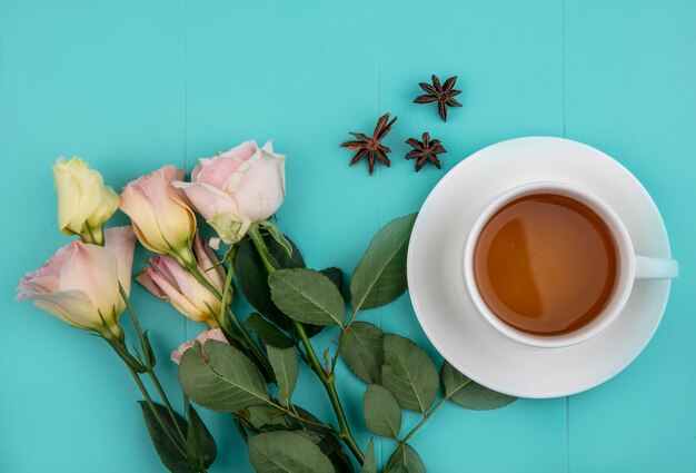 Top view of cup of tea and flowers on blue background