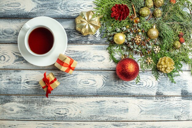 Top view a cup of tea gifts fir tree branches on wooden background