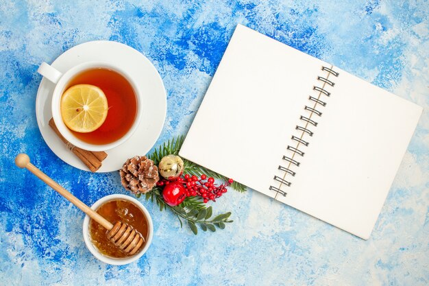 Top view cup of tea honey in bowl notebook on blue table