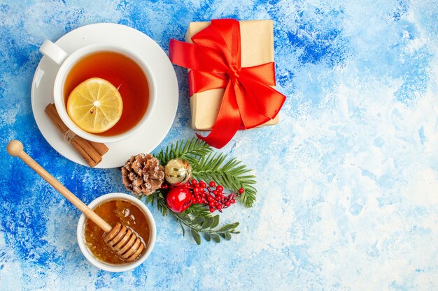 青いテーブルの空き領域にボウルクリスマスツリーの枝にお茶の蜂蜜のトップビューカップ