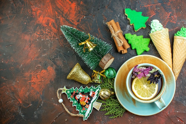 짙은 빨간색 테이블에 있는 상위 뷰 차 아이스크림 계피 스틱 크리스마스 트리 쿠키 크리스마스 장식품