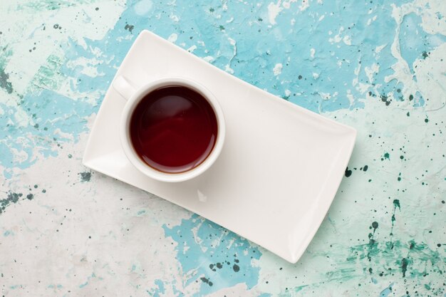 Vista dall'alto tazza di tè all'interno della tazza e del piatto sulla scrivania azzurra