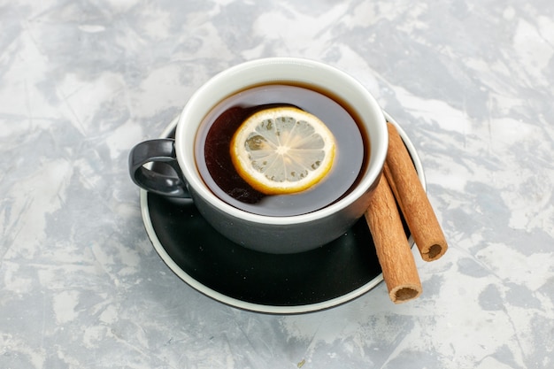 Top view cup of tea inside cup and plate with cinnamon on white surface