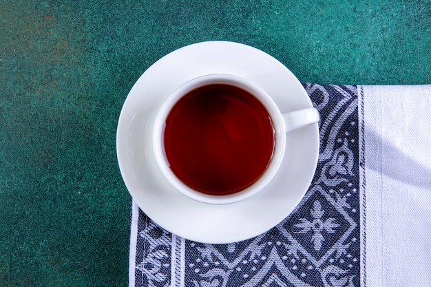 Top view cup of tea on kitchen towel on green