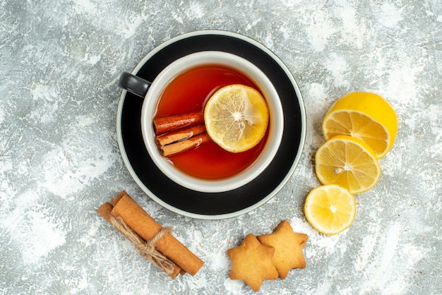 Top view a cup of tea lemon slices cinnamon sticks cookies on grey surface with free space